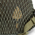 Gros plan de l'insigne du 506th PIR du casque complet parachutiste M1-C original avec sa coque McCord 884C et son liner Westinghouse, marquage 506th PIR 2nd bn NCO avec son filet petites mailles monté dessus.