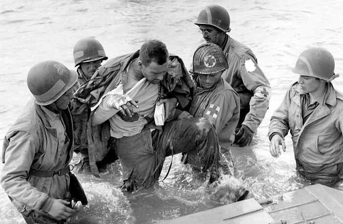 Medics US avec leurs casque US à marquage qui aident un soldat US blessé à sortir de l'eau a