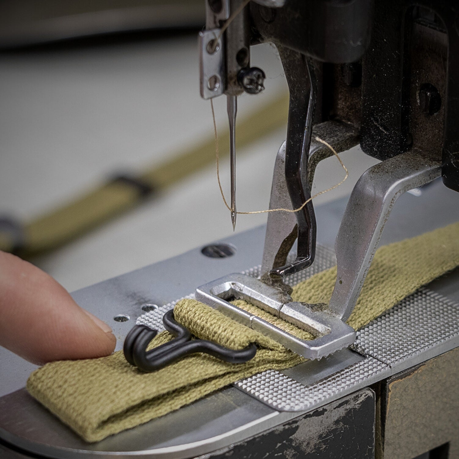 Couture d'un crochet de jugulaire de casuqe US M1 avec un machine à point d'arrêt.